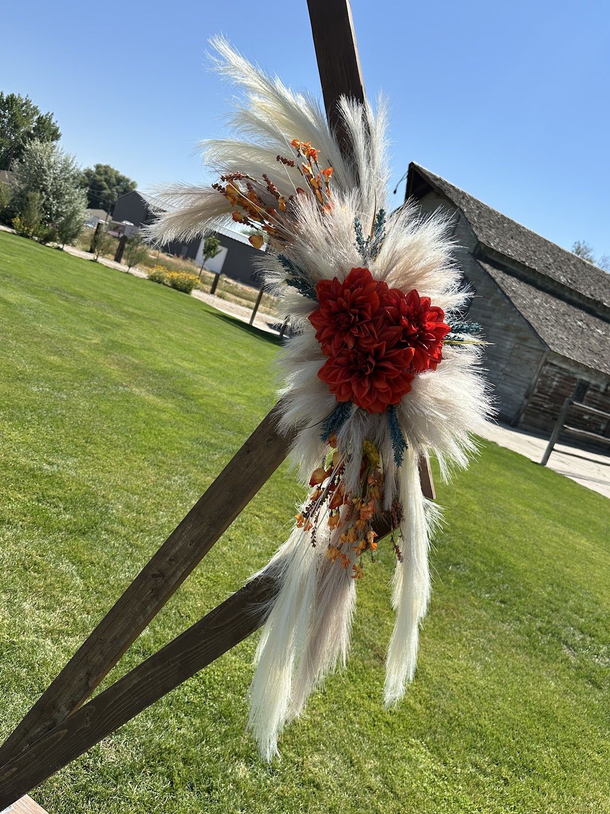 A pampas grass and red dahlia detail from a wedding arch