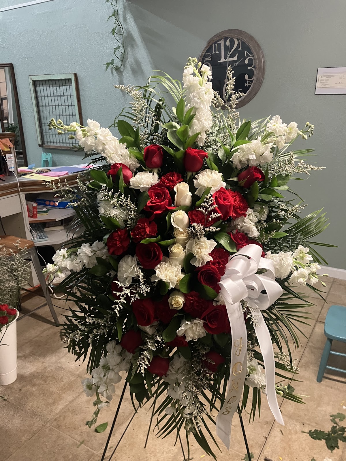 A red and white standing funeral spray of roses and carnations from Buttercup Barley's
